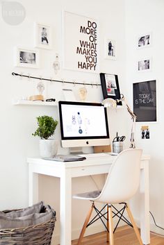 a white desk with a computer on top of it next to a basket filled with plants