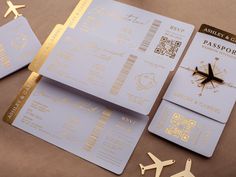 two passport cards with gold foil on them next to an airplane and some paper clips