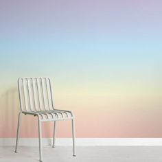 a white chair sitting in front of a wall with a pastel background on it