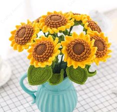 a blue vase filled with yellow sunflowers on top of a white tablecloth