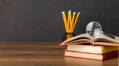 an open book with magnifying glass sitting on top of it next to pencils