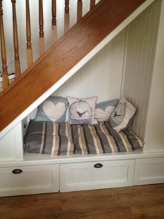 a dog bed under stairs with pillows on it