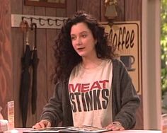 a woman standing in front of a counter talking to someone