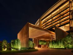 an exterior view of a hotel at night with lights on and trees in the foreground