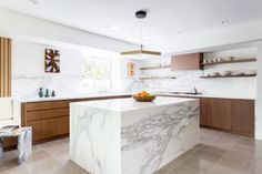 a large kitchen with marble counter tops and wooden cabinetry, along with an island in the middle