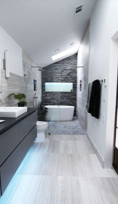 a modern bathroom with grey and white tile on the walls, wood flooring and tub