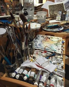 an artist's easel filled with lots of paint and brushes, watercolors