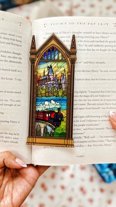 an open book with stained glass depicting a train passing through a castle on the window