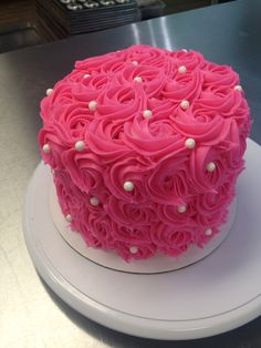 a cake with pink icing and white pearls sits on top of a countertop