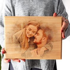 a woman holding a wooden photo frame with a man's face on it