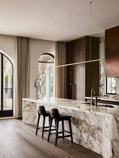 a kitchen with marble counter tops and bar stools in front of an open window