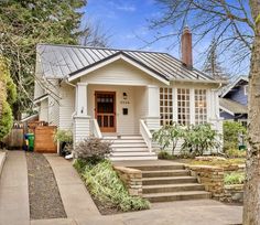 a small white house with steps leading up to the front door