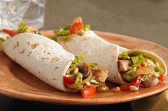 two burritos on a plate next to a glass of water