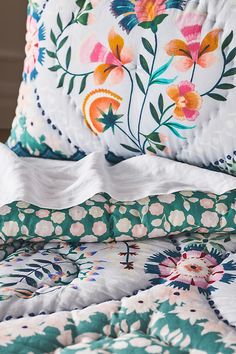 a close up of a flowered bed with white sheets and pillows on top of it