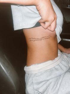 a woman with a tattoo on her stomach pointing at the word love in cursive writing