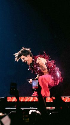 the man is performing on stage with his legs spread out and hands in the air