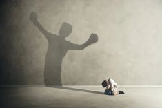 a man kneeling down in front of a shadow of a person holding a tennis racquet