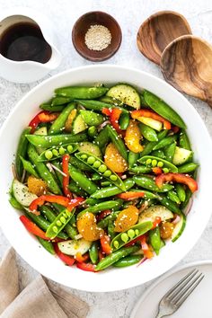 a white bowl filled with green beans and veggies next to two wooden spoons