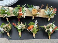 a bunch of flowers are arranged on a piece of driftwood and placed on a table