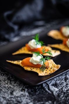 small appetizers are arranged on a black plate