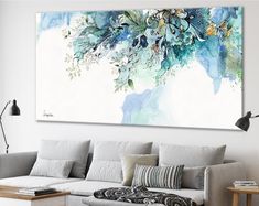 a living room with a couch, coffee table and large painting on the wall above it