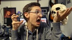 a man holding up a fake human skull in front of his face