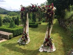 two floral decorated archways in the middle of a garden