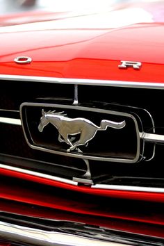 the front end of a red car with a horse emblem on it's grille