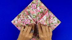 someone is folding an origami flowered paper into a square shape with their hands