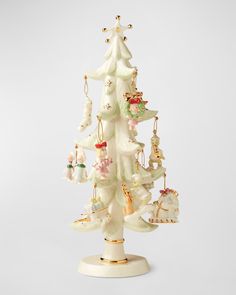 a white christmas tree with ornaments hanging from it's sides on a stand against a white background