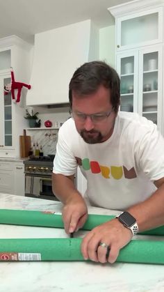 a man cutting green paper on top of a counter