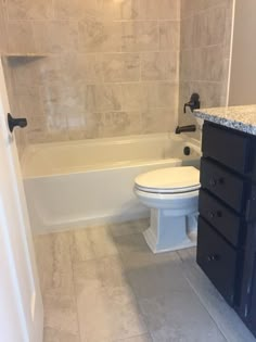 a white toilet sitting next to a bath tub in a bathroom