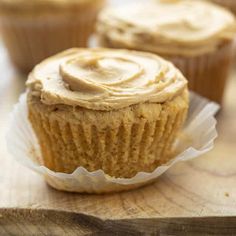 cupcakes with frosting sitting on top of a wooden cutting board