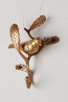 a gold bird on a branch with leaves attached to it's back wall hook