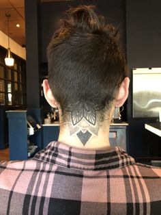 the back of a man's head with a tattoo on his neck and chest