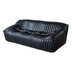 a black leather couch sitting on top of a white floor