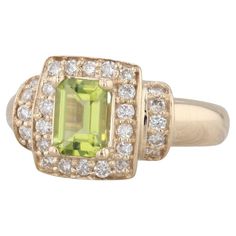 an 18k yellow gold ring with green and white diamonds on the sides, set with a square cut peridolite surrounded by small round brilliant pave stones