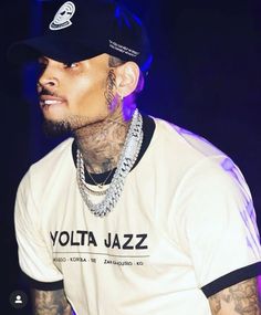 a man with tattoos wearing a white shirt and black hat