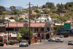 cars are driving down the street in front of buildings and hills with trees on top