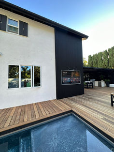 a house with a wooden deck next to a swimming pool