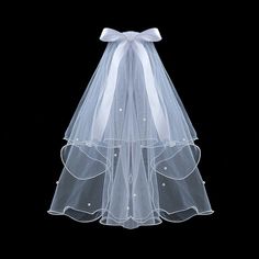 a white veil with pearls on the bottom and a bow at the top is shown in front of a black background