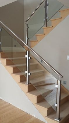 a stair case with glass balustrades and wood flooring in a house