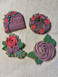 three decorated cookies sitting on top of a white towel next to each other, with the words happy birthday written in purple frosting