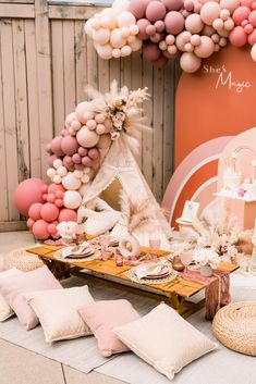 a table topped with lots of pink and white balloons