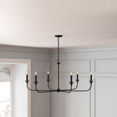 a black chandelier hanging from the ceiling in a dining room with white walls