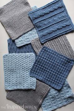 several knitted squares are arranged together on the table, one is blue and gray