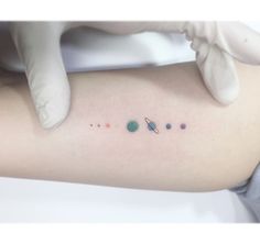 a woman's arm with small planets on it