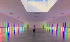 a woman is walking through an empty room with colorful lights on the walls and ceiling