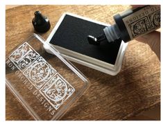 an ink pen is being used to write on a stamp pad next to a glass container