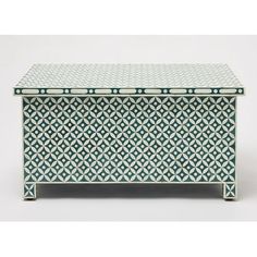 a green and white box with geometric designs on it's sides, sitting on a table